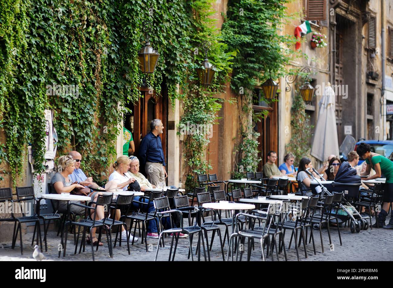 ROMA, ITALIA - MAGGIO 2011: Turisti e locali seduti in un ristorante all'aperto. Una strada pedonale affollata piena di gente durante l'estate nel centro Foto Stock