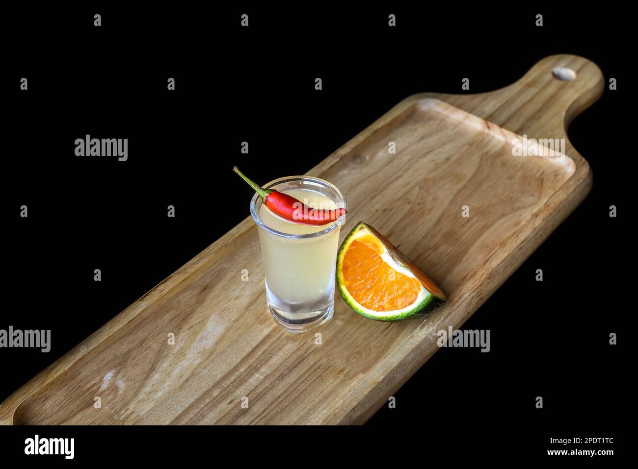 Shot di alcool fatto di succo d'arancia e peperoncino su tavola di legno con spazio copia Foto Stock