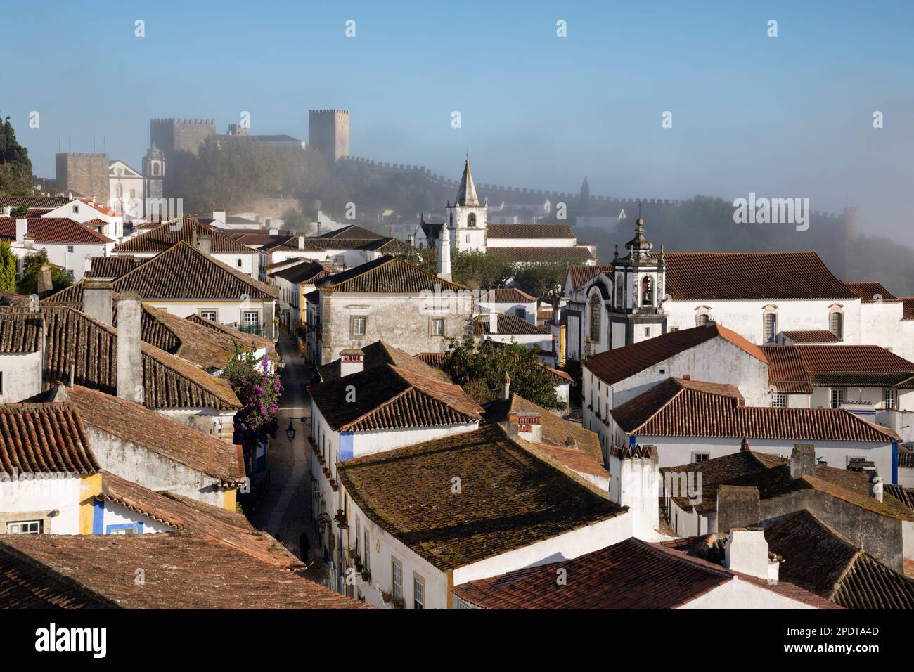 Vista lungo Rua Direita nella città vecchia e le mura di Obidos in nebbia mattutina, Obidos, Regione Centrale, Portogallo, Europa Foto Stock