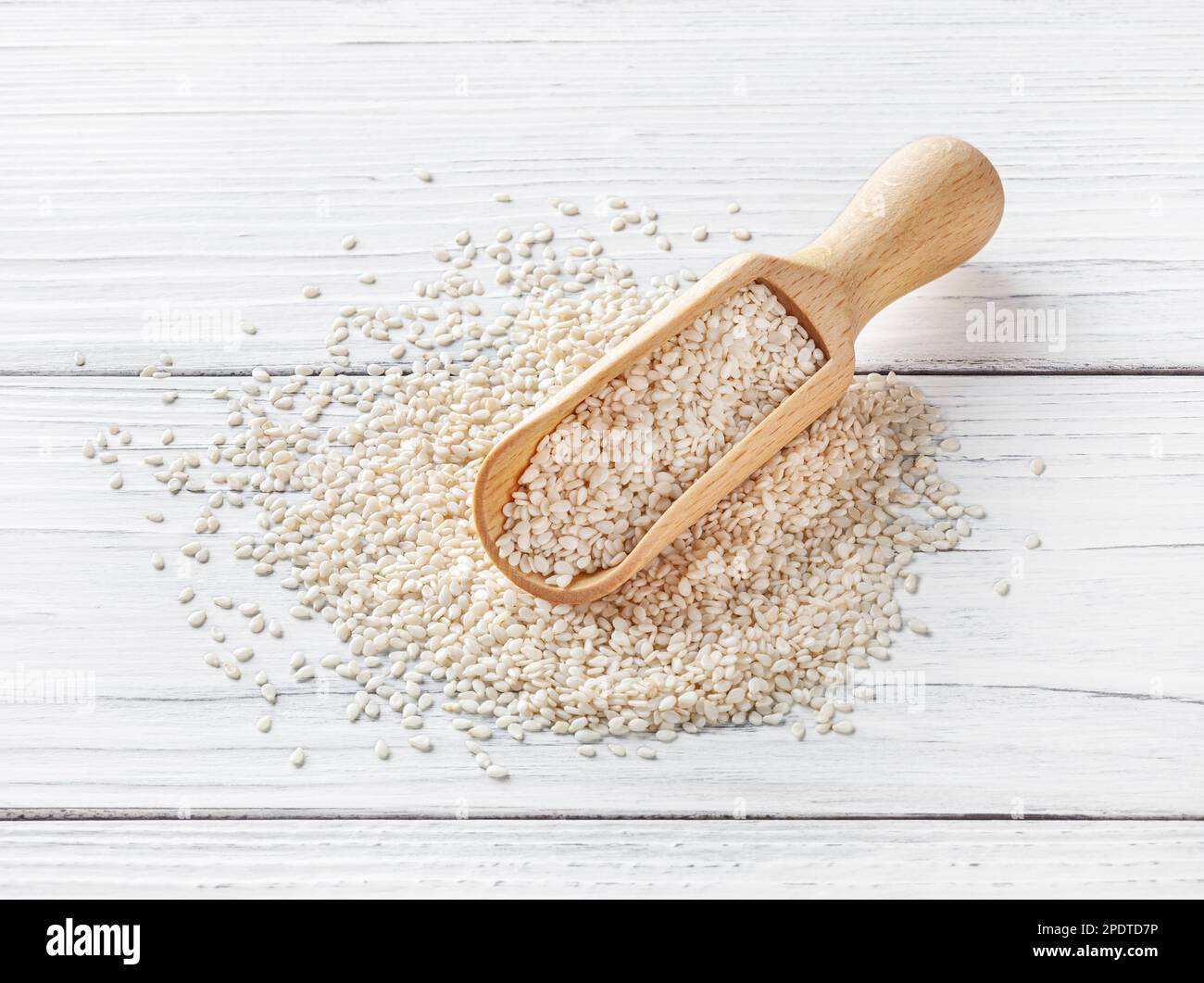 Semi di sesamo secchi in ciotola di legno su sfondo bianco di legno Foto Stock