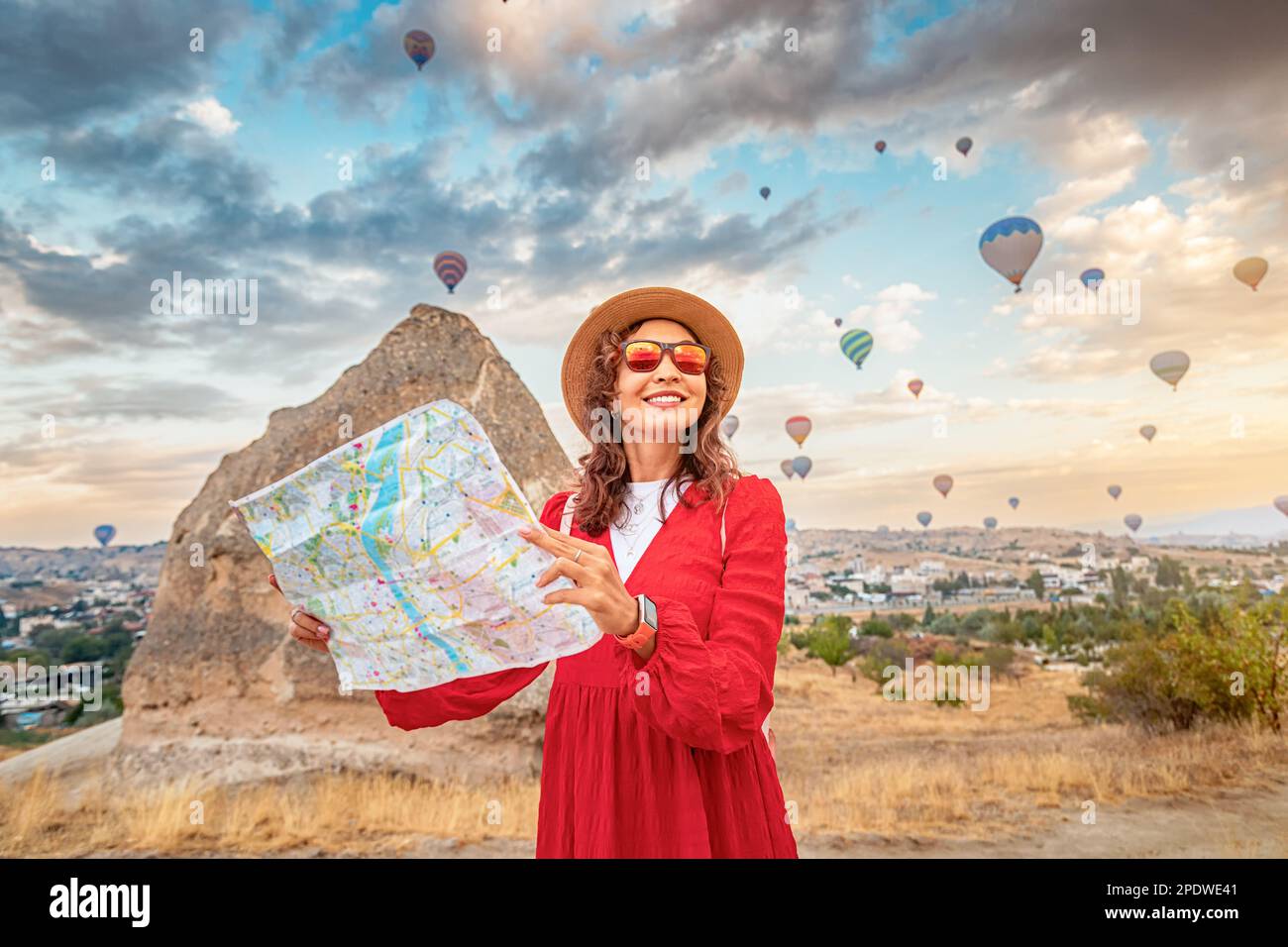 Un turista femminile determinato con una mappa in mano guarda ai mongolfiere sbalorditivi in Cappadocia. Foto Stock