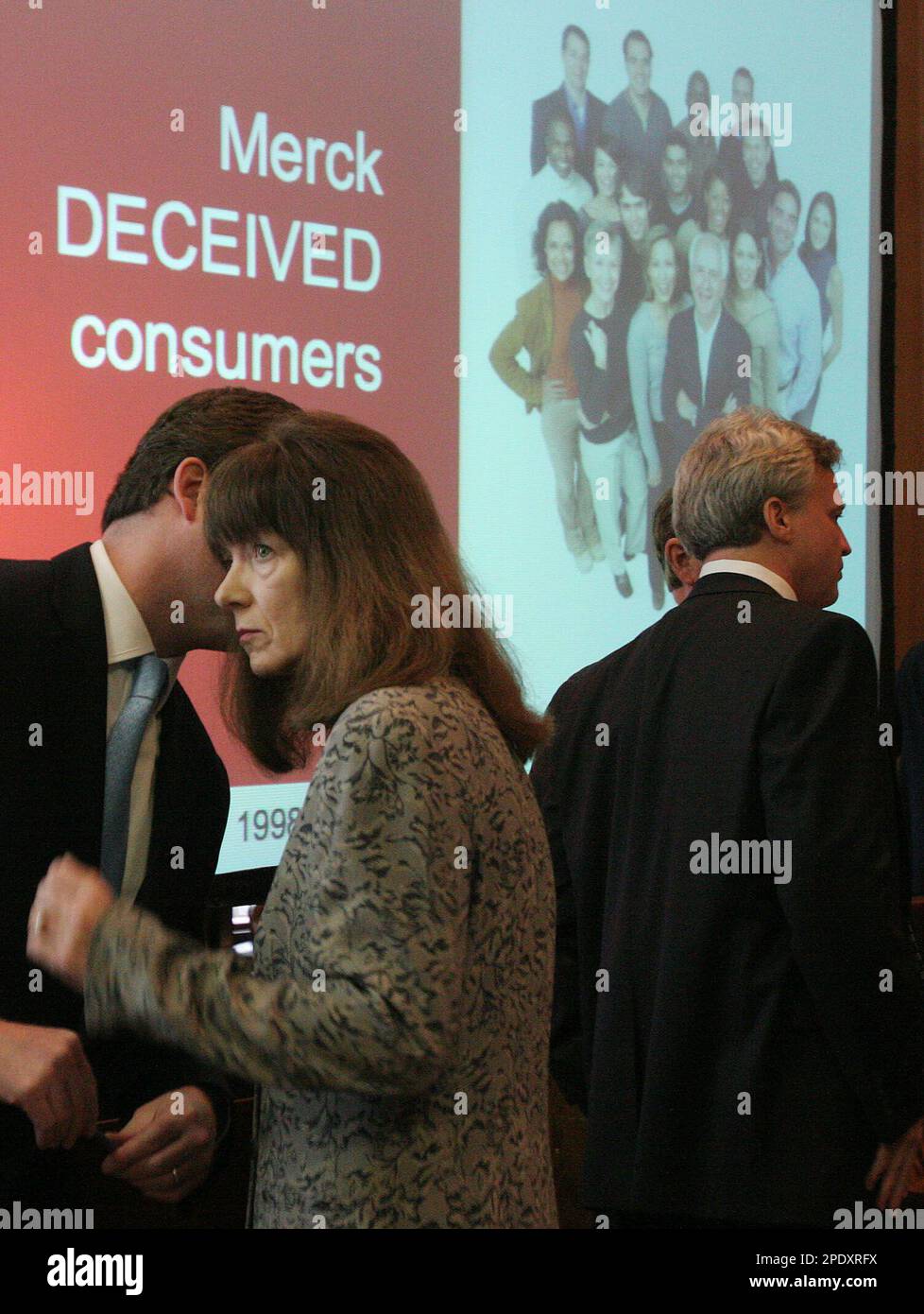 Merck Co. attorney Gerry Lowry, left, speaks with an unidentified cohort as she and co-counsel David Kiernan, right, stand in front of video screen being used by plaintiff attorney Marl Lanier in his closing argument in the case against the Vioxx maker Wednesday, Aug. 17, 2005, in Angleton, Texas. (AP Photo/Pat Sullivan) Foto Stock