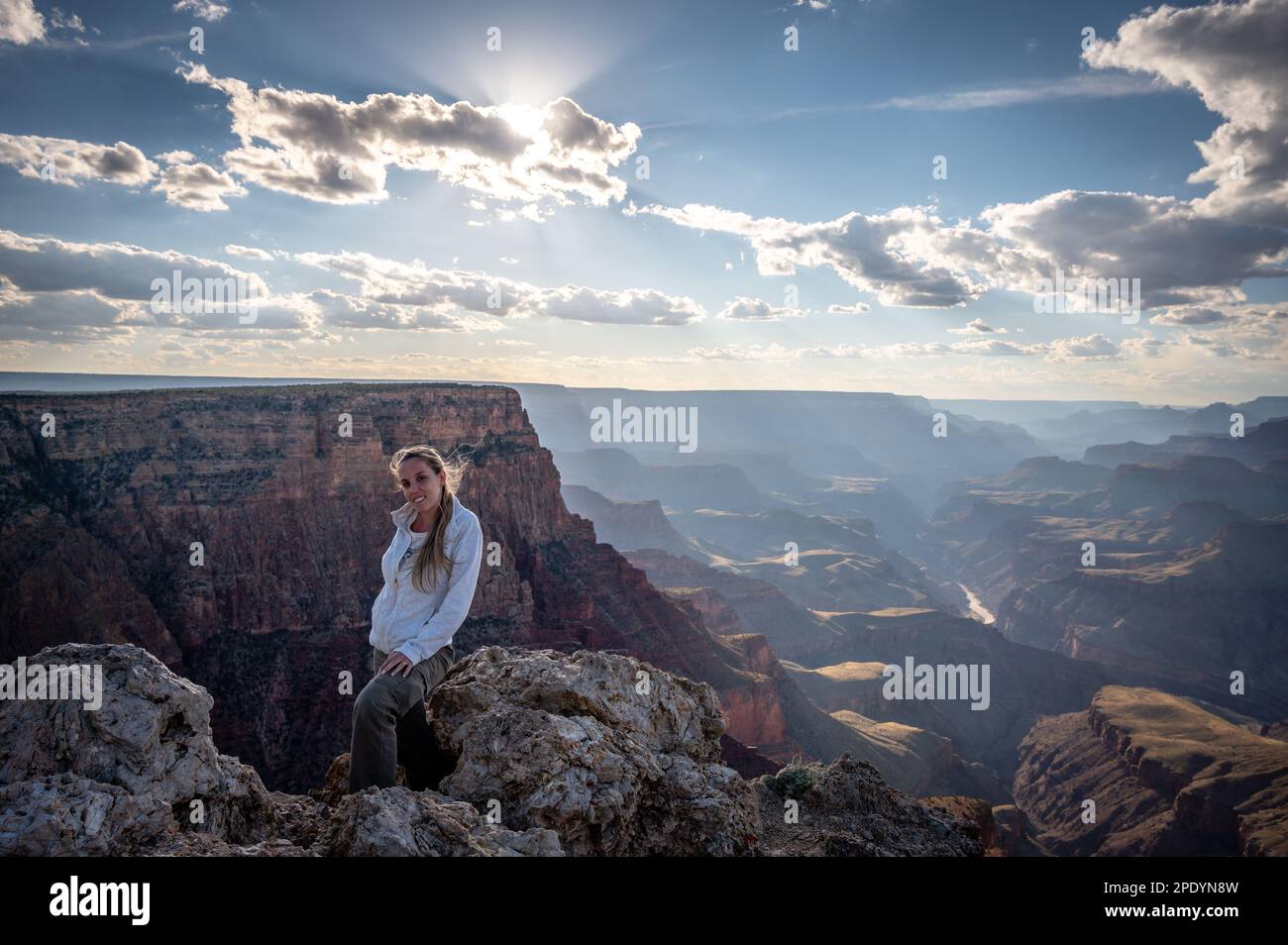 Una giovane bionda che sta in piedi sul bordo del precipizio del Grand canyon, sta guardando la telecamera Foto Stock