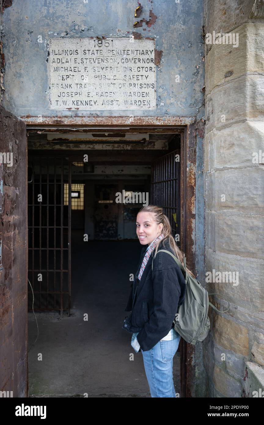 Giovane ragazza bionda sorridente al cancello d'ingresso della prigione di Old Joliet, sta visitando le vecchie strutture Foto Stock