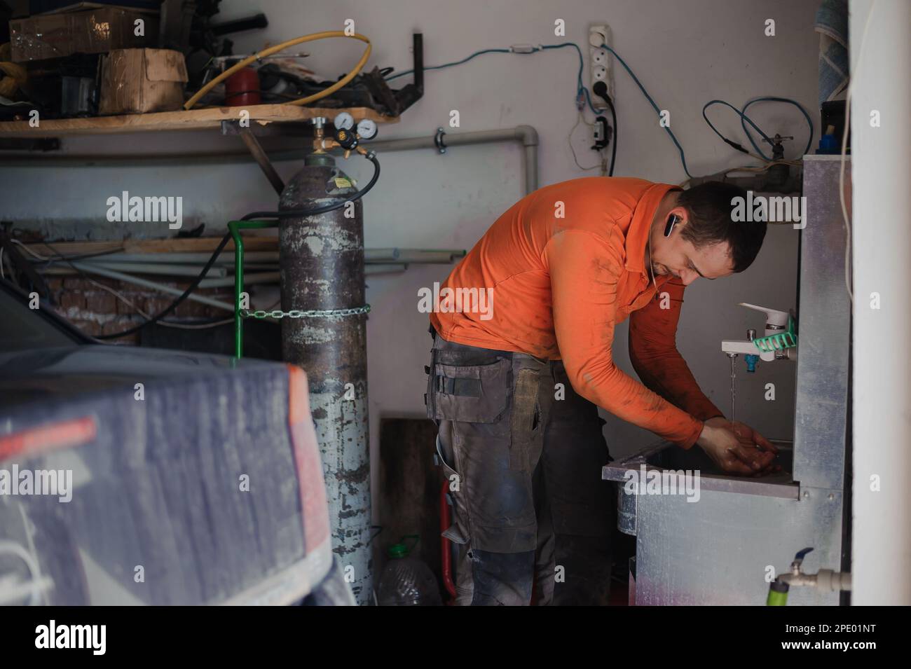 Meccanico auto maschio lavando le mani dopo la riparazione dell'automobile. L'operaio si lava le mani Foto Stock