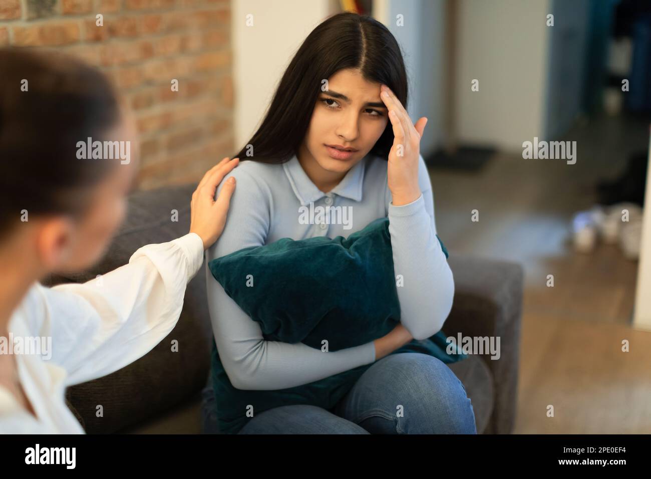 Signora teen infelice che ha problema, abbracciando cuscino e parlando con un amico che mostra compassione e cercando di appagare Foto Stock