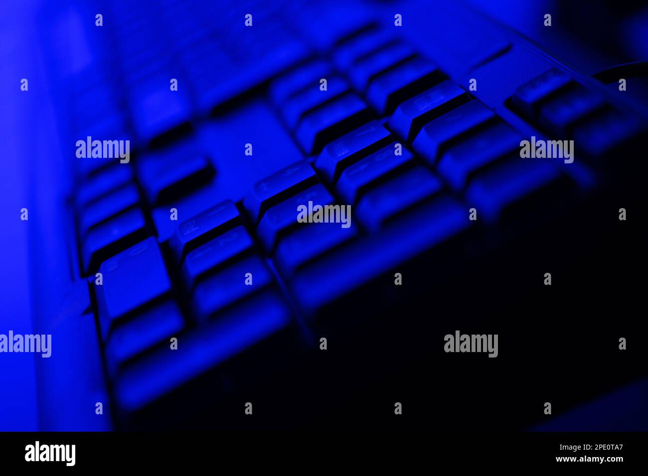 Primo piano della tastiera del computer desktop illuminata in blu scuro Foto Stock
