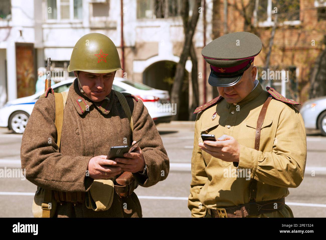 Khabarovsk, Russia - 9 maggio 2017: Due uomini che indossano divisa militare vintage, che testano gli smartphone. Divertenti e incongrui soldati dell'URSS che reggono i cellulari Foto Stock