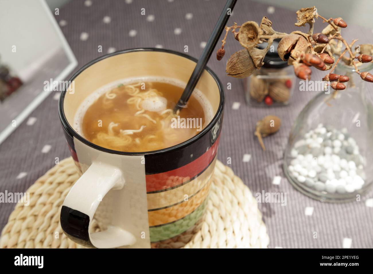 Appena cucinato spaghetti caldi istantanei in una tazza con una forchetta, pronto a mangiare. Colazione veloce a buon mercato a casa da sola in un'atmosfera accogliente Foto Stock