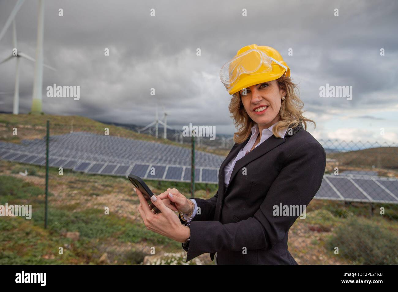 Un ingegnere utilizza il suo smartphone al lavoro in una centrale solare Foto Stock Un ingegnere utilizza il suo smartphone al lavoro in una centrale solare Foto Stock
