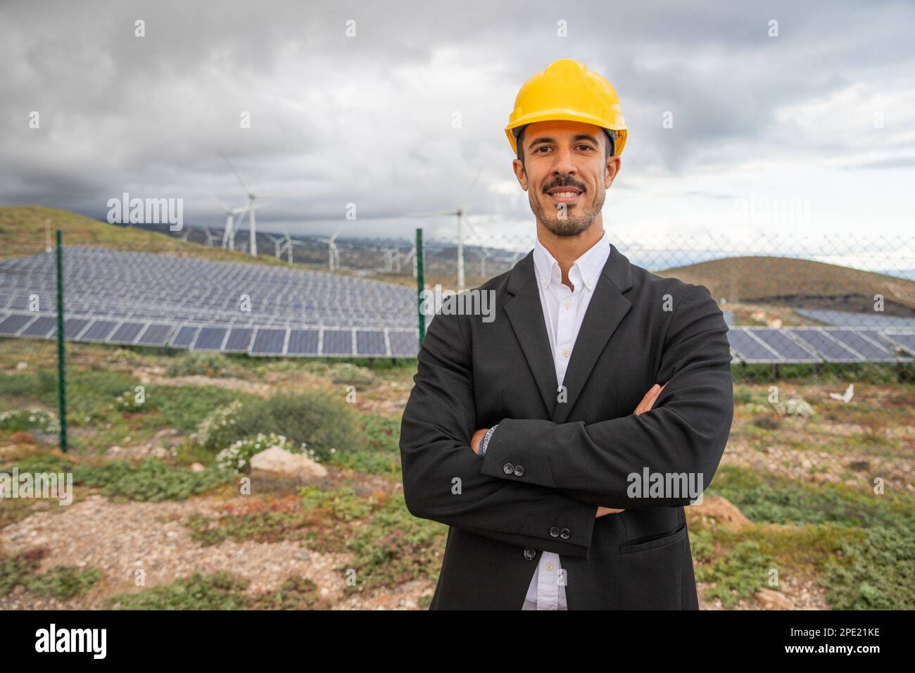 Un ingegnere di una centrale solare elegantemente vestito indossa un casco protettivo. Foto Stock Un ingegnere di una centrale solare elegantemente vestito indossa un casco protettivo. Foto Stock