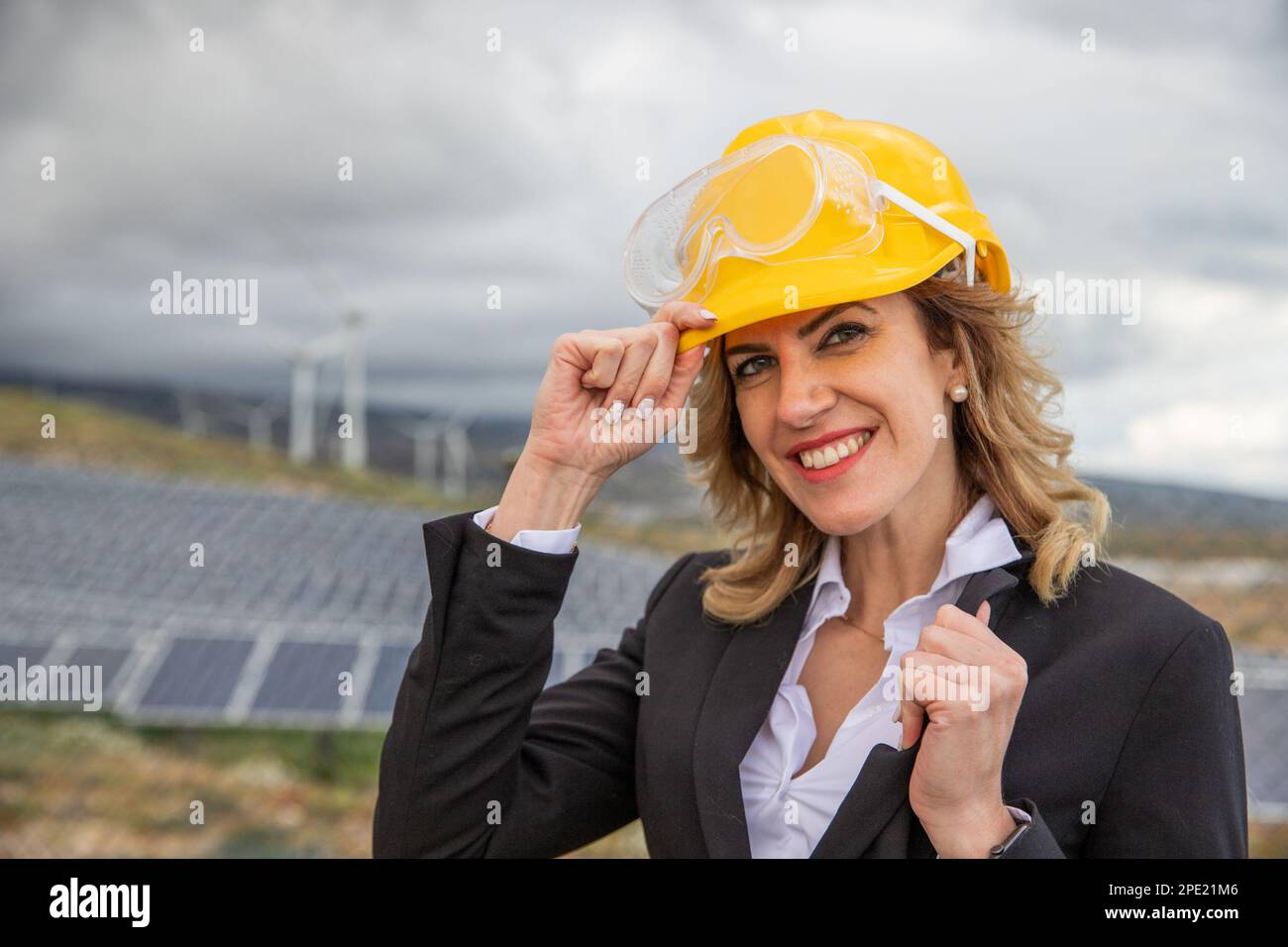 Un'ingegnere donna sorridente indossa un casco protettivo presso una centrale solare Foto Stock Un'ingegnere donna sorridente indossa un casco protettivo presso una centrale solare Foto Stock