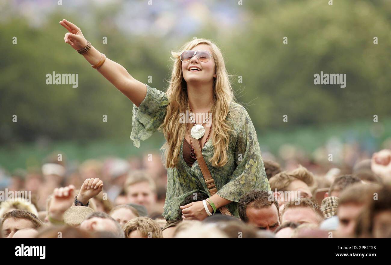 A festival goer watches one of the bands from the shoulders of a friend at the Glastonbury music festival, Glastonbury, England, Saturday, June 25, 2005. Despite torrential rain on the previous day the festival was back on track after organisers arranged fresh camping areas for those flooded out of their tents. (AP Photo/Jon Super) Foto Stock