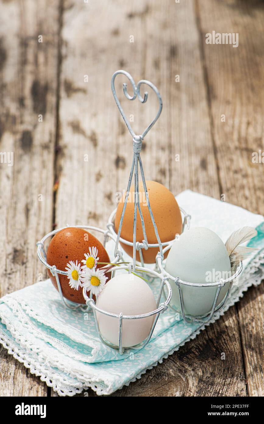 Uova di Pasqua colorate in un piccolo cestino di uova di metallo su un tavolo di legno Foto Stock