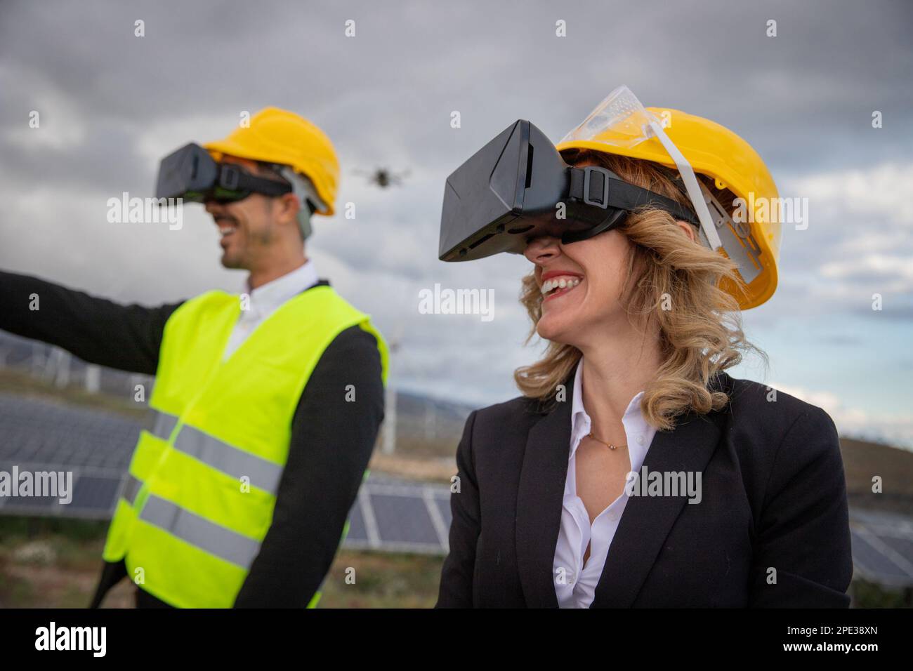 Due ingegneri lavorano utilizzando cuffie per la realtà virtuale in una centrale a energia solare. Foto Stock Due ingegneri lavorano utilizzando cuffie per la realtà virtuale in una centrale a energia solare. Foto Stock