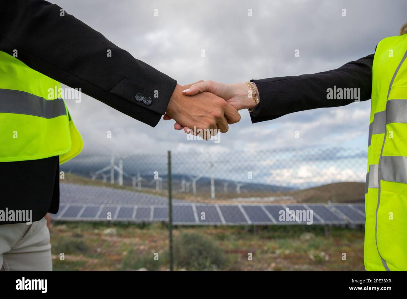 Due uomini d'affari che scuotono le mani in una fattoria solare, manager femminili e maschili. Foto Stock Due uomini d'affari che scuotono le mani in una fattoria solare, manager femminili e maschili. Foto Stock