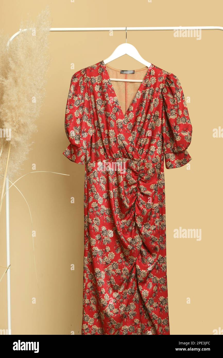 Abiti da donna. Appendiabiti con elegante ed elegante abito in seta floreale in atelier di moda. Pezzi di moda senza tempo di buona qualità. Foto Stock