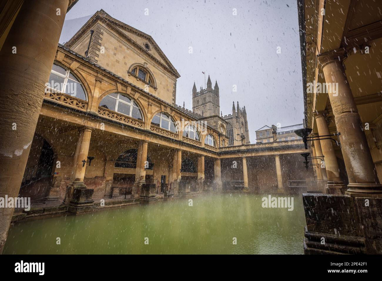 Neve che cade sul grande bagno alle terme romane a Bath, Somerset Foto Stock