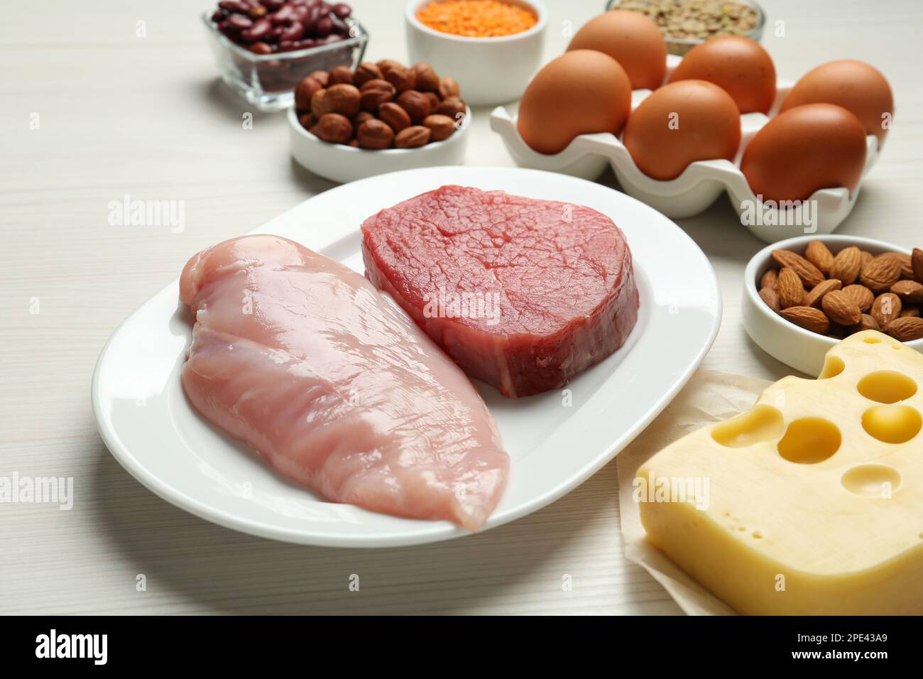 Carni fresche ed altri prodotti su tavola di legno bianco, primo piano. Fonti di amminoacidi essenziali Foto Stock