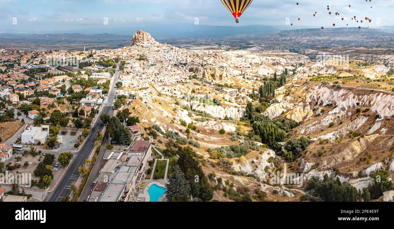 Le colline ondulate della Valle dei Pigoni della Cappadocia, incorniciate dall'imponente Castello di Uchisar, creano un'immagine impressionante con i mongolfiere Foto Stock