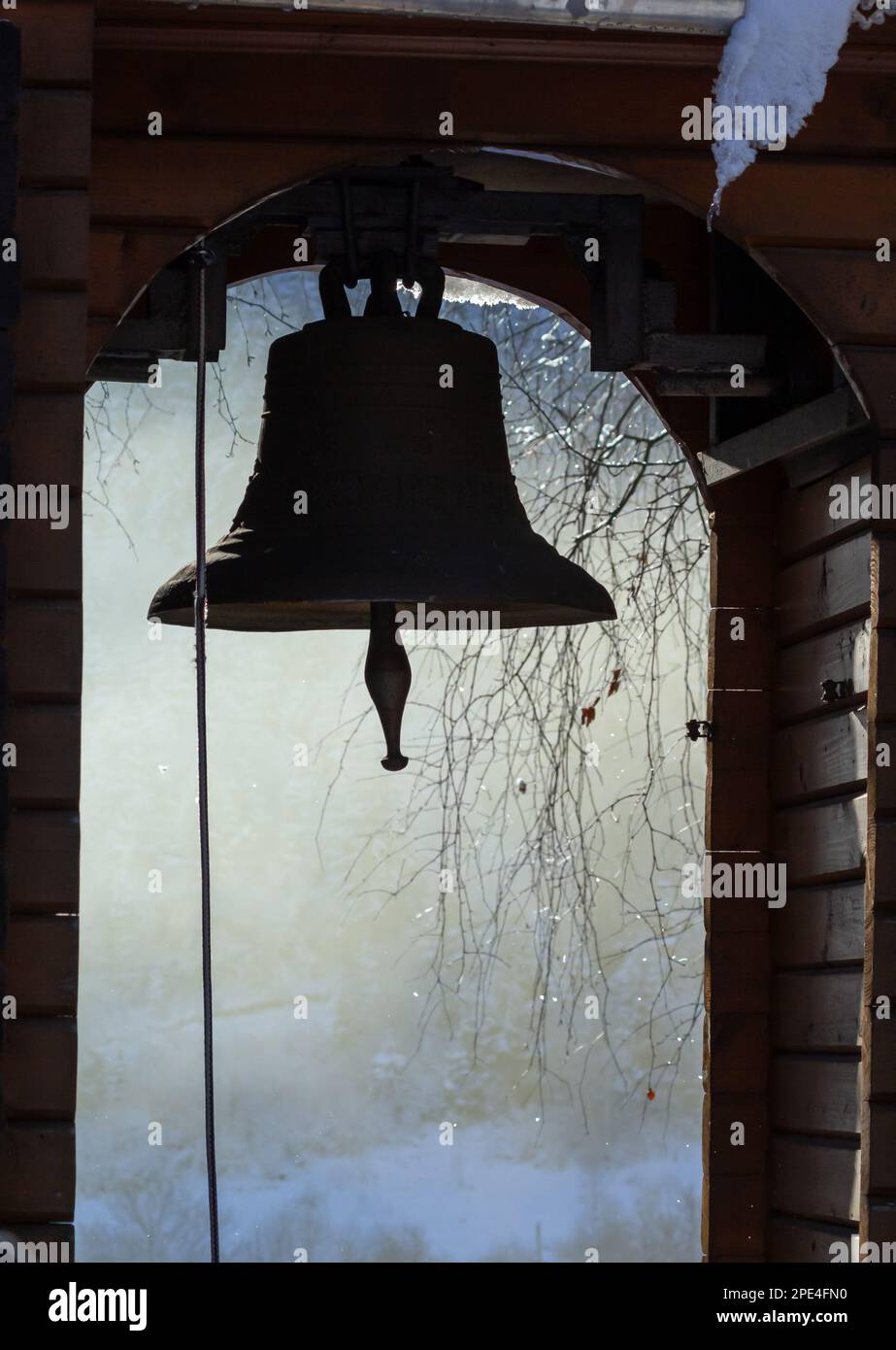 Vista delle montagne innevate, attraverso la campana della chiesa, che si trova nel piccolo villaggio di Kryvorivnya nei Carpazi ucraini. Foto Stock