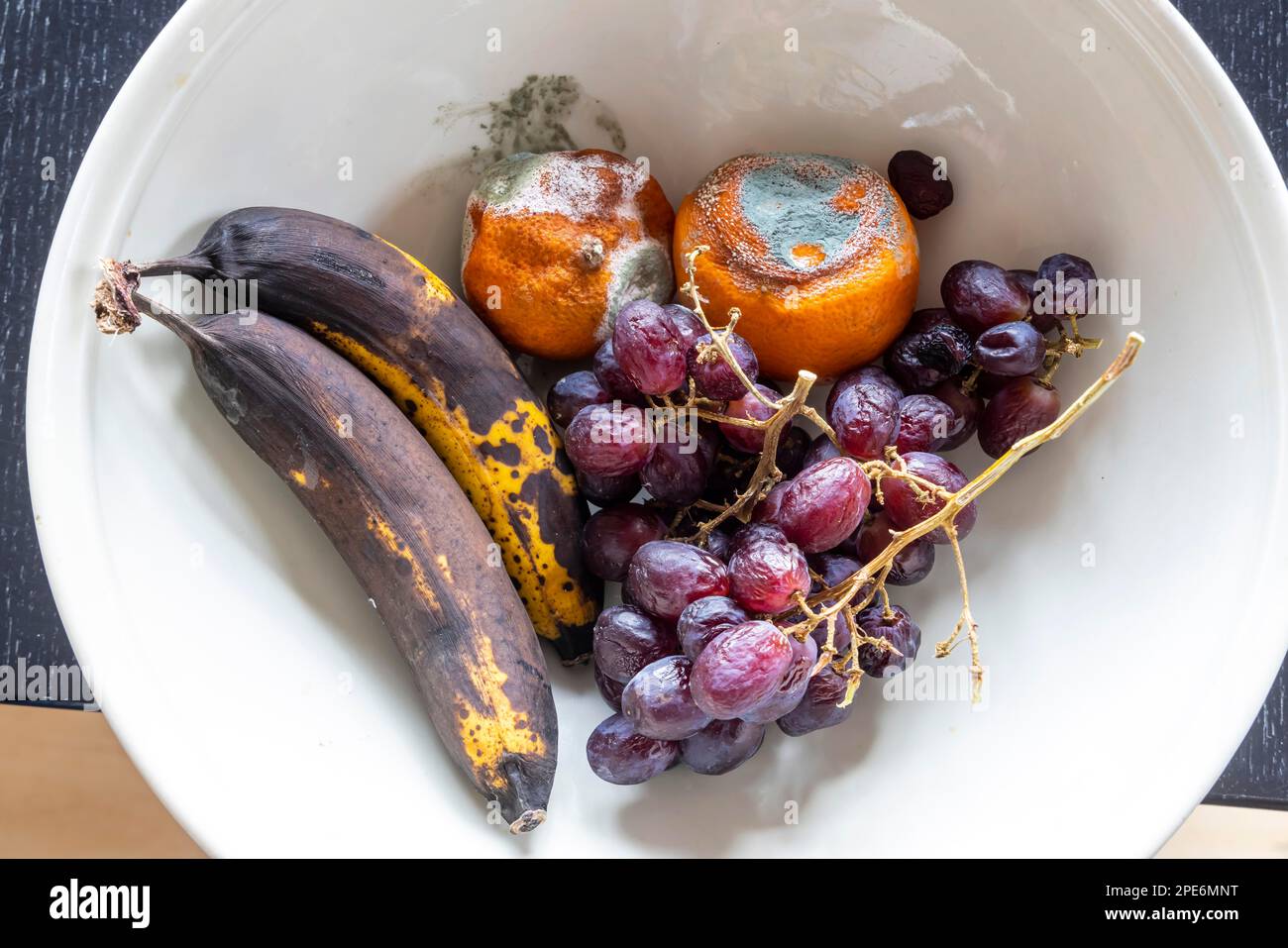 Muffa la frutta in una ciotola, mandarino, uva, banana Foto Stock