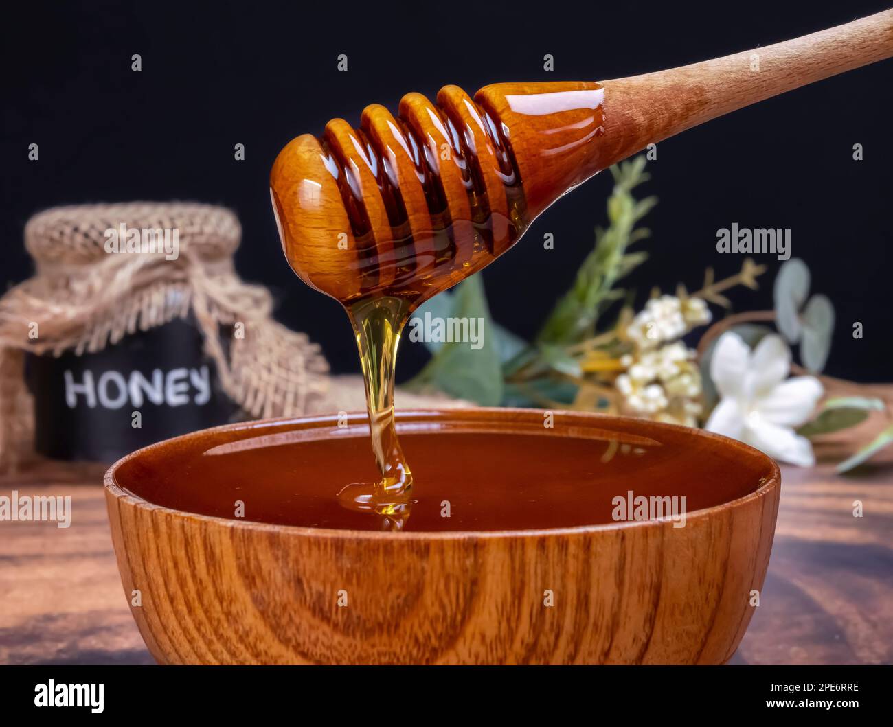 Cucchiaio di miele che esce dall'arco pieno di miele. Il miele contiene molti nutrienti, antiossidanti, migliora la salute del cuore, cura delle ferite, offre antidepressivi Foto Stock