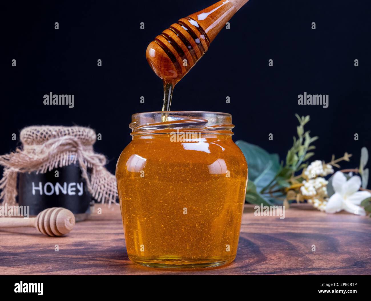 Cucchiaio di miele che esce dal vaso pieno di miele. Il miele contiene molti nutrienti, antiossidanti, migliora la salute del cuore, cura delle ferite, offre antidepressivi Foto Stock