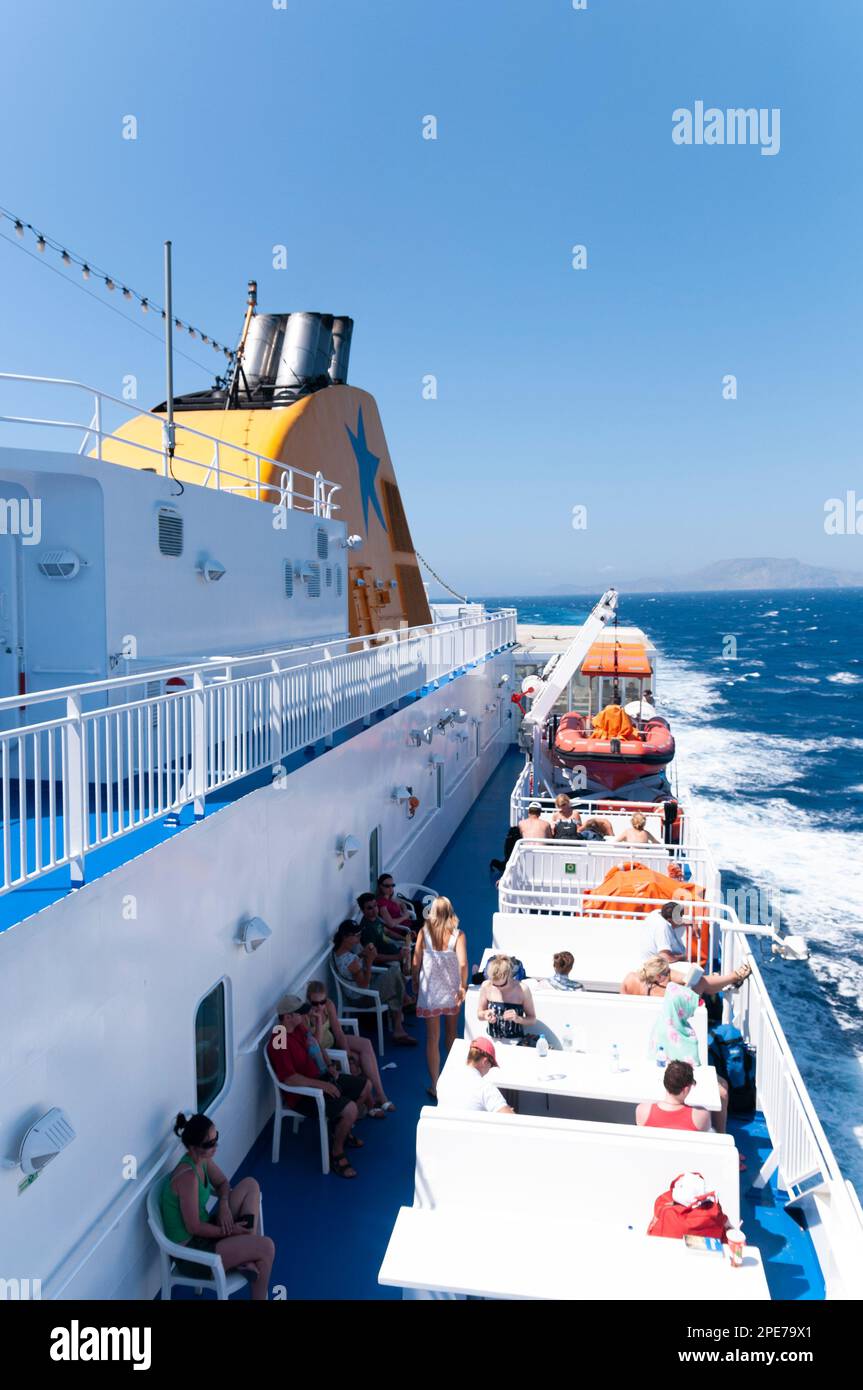 Gruppo di turisti seduti su un ponte scoperto di un traghetto che naviga nel Mar Mediterraneo in Grecia Foto Stock