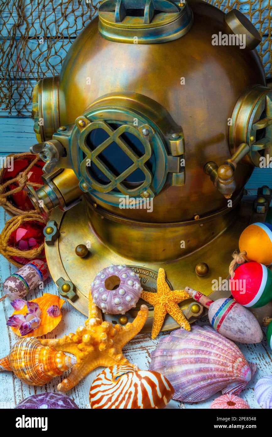 Casco da subacquea e conchiglie con galleggianti in vetro e vecchie reti. Deep-Sea Divers casco in ottone pesante di grandi dimensioni, utilizzato per l'esplorazione di acque profonde e lascia il subacqueo b Foto Stock