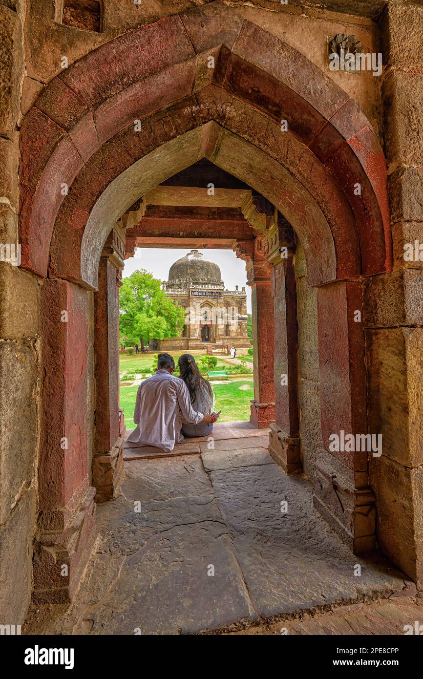 Giovane coppia ammirando lo Shish Gumbad mentre si siede in un arco del Bara Gumbad nel Giardino di Lodhi Foto Stock