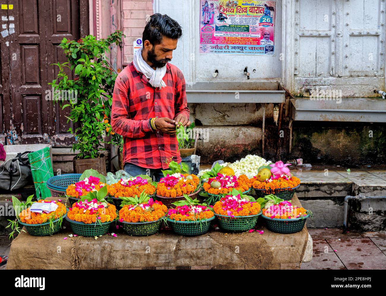 Uomo che vende ghirlande di fiori dai colori vivaci al di fuori di un tempio Chandni Chowk nella Vecchia Delhi Foto Stock