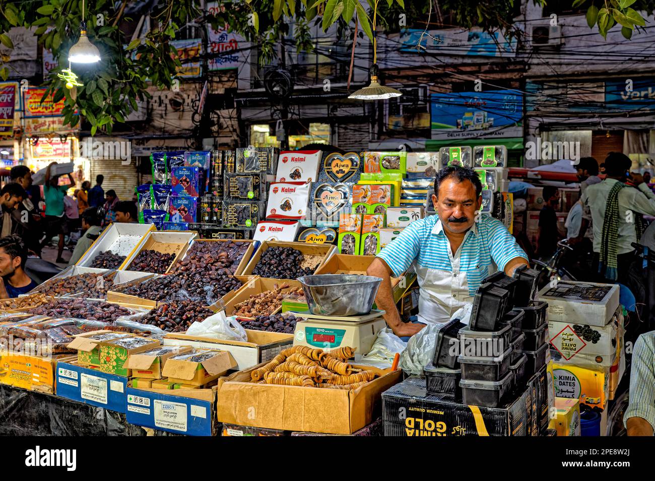 Un venditore vende noci, frutta secca e molte spezie diverse nel suo negozio nel mercato delle spezie nella Vecchia Delhi Foto Stock