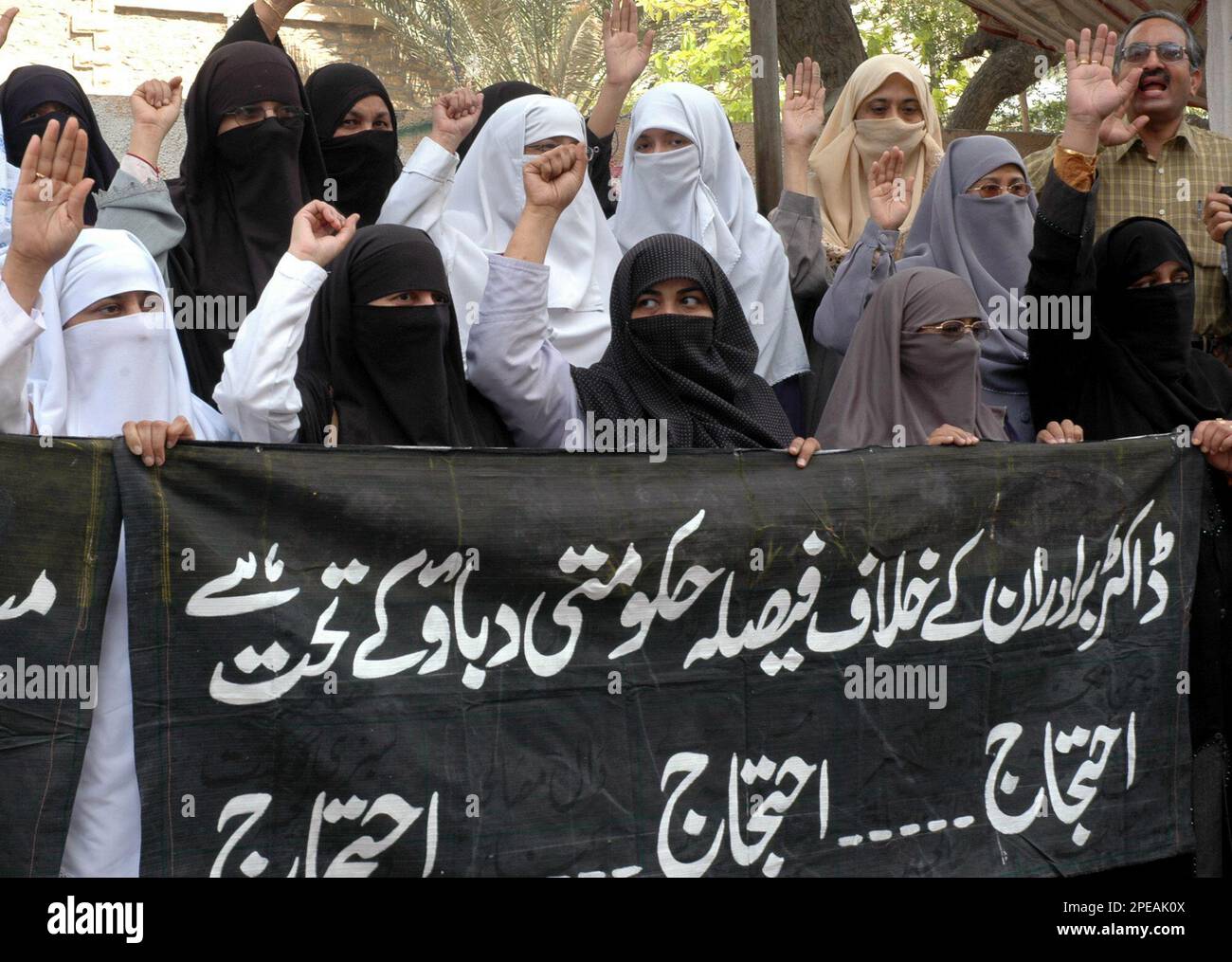Pakistani female doctors hold a banner that reads: "The court decision against doctor brothers is due to government pressure" at a rally to protest the court decision against brothers in Karachi, Pakistan, Tuesday, March 15, 2005. Pakistan's court on Monday sentenced the two physicians to seven years in prison after convicting them of giving money and medical treatment to Islamic militants. (AP Photo/Shakil Adil) Foto Stock