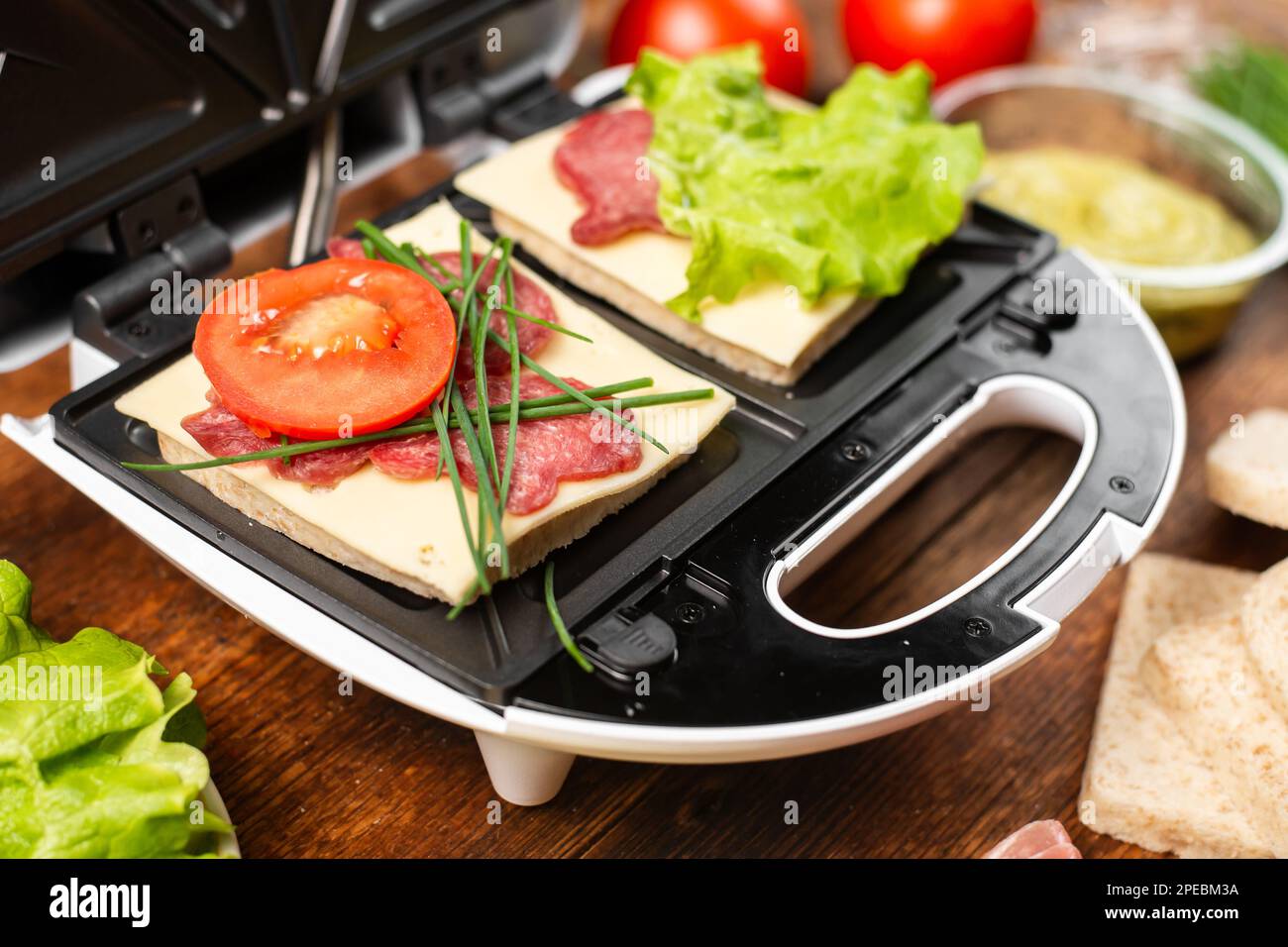 Una panettiera con due diversi panini con pomodori, prosciutto, cipolle e formaggio. Preparare un pasto leggero. Foto Stock