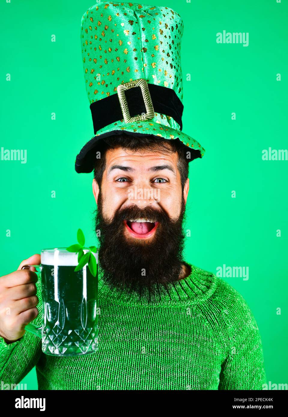 Felice uomo bearded in leprechaun cappello bere birra nel pub o bar. Festa di San Patrizio. Uomo sorridente con un bicchiere di birra verde. Bevanda verde Foto Stock