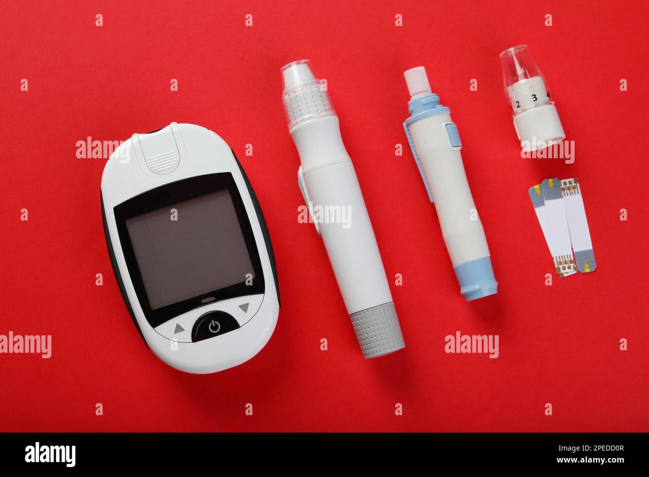 Glucometro digitale, penne a lancetta e strisce reattive su sfondo rosso, piatto. Controllo del diabete Foto Stock