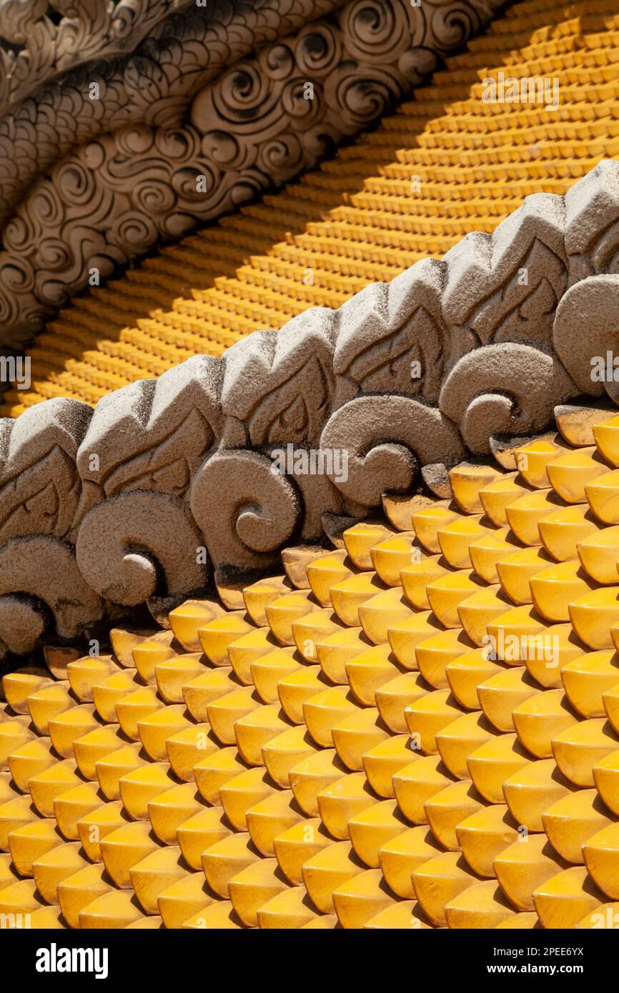Tetto del tempio buddista asiatico piastrellato con piastrelle gialle e decorato con sculture di drago. Pagoda thailandese tetto ornamentale come un colorato abrac testurizzato Foto Stock