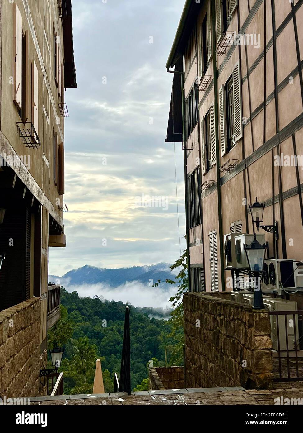Colmar tropicale, Malesia. 02nd Mar, 2023. Attraverso due case a graticcio, i wafer di nebbia possono essere visti sopra la giungla delle colline di Berjaya. A un'ora di auto a nord-est della capitale Kuala Lumpur sorge una replica della città di Colmar, patrimonio dell'umanità dell'Alsazia. Il clone nella foresta pluviale è stato costruito nel 1990s su richiesta dell'ex capo di governo Mahathir Mohamed e da allora ha deliziato i visitatori da vicino e lontano. (A dpa: Colmar tropicale: Un pezzo di Alsazia nella giungla della Malesia) Credit: Carola Frentzen/dpa/Alamy Live News Foto Stock