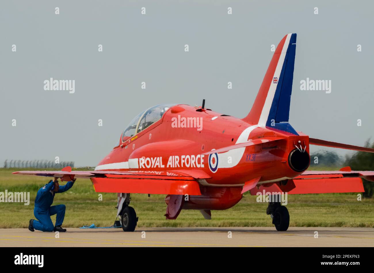 Royal Air Force Red Arrows display team BAe Hawk T1 jet plane in partenza per l'esposizione al RAF Scampton, con il membro dell'equipaggio di terra che controlla sotto l'ala Foto Stock