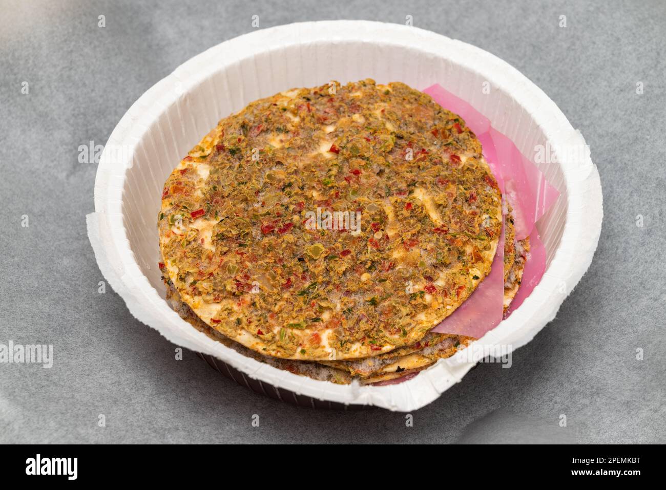 un lahmacun surgelato pronto da mangiare su carta da forno su una teglia da forno Foto Stock