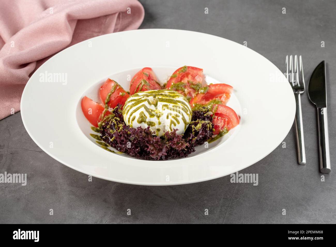 Burrata con pomodori e verdure fresche su piatto di porcellana bianca Foto Stock