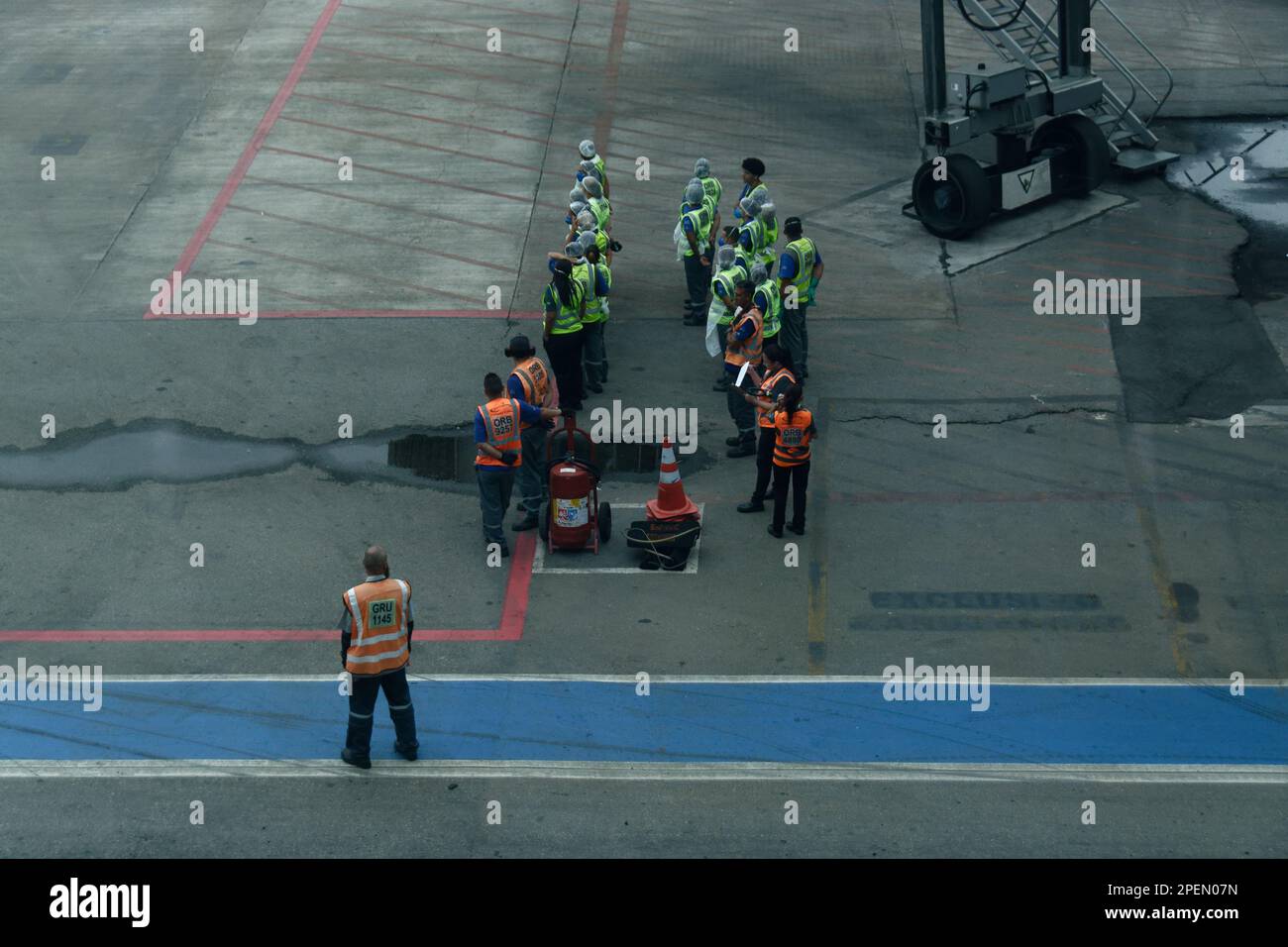 Pulizia degli aeromobili e rifornimento degli equipaggi in attesa dell'arrivo dell'aeromobile sul asfalto. Indossare giubbotti di sicurezza riflettenti. Aeroporto di San Paolo/Guarulhos Foto Stock