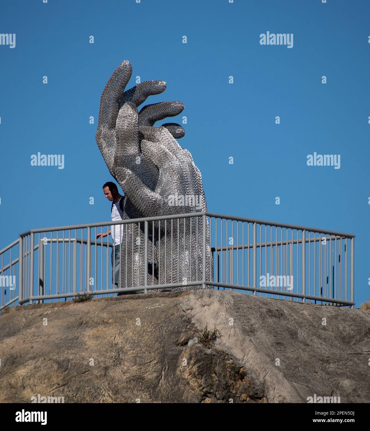 Scultura 'queste mani' di Michael Van Dam, in cima alla roccia al festival Swell Sculpture Currumbin, Gold Coast Queensland, Australia 2016 con visitatore. Foto Stock