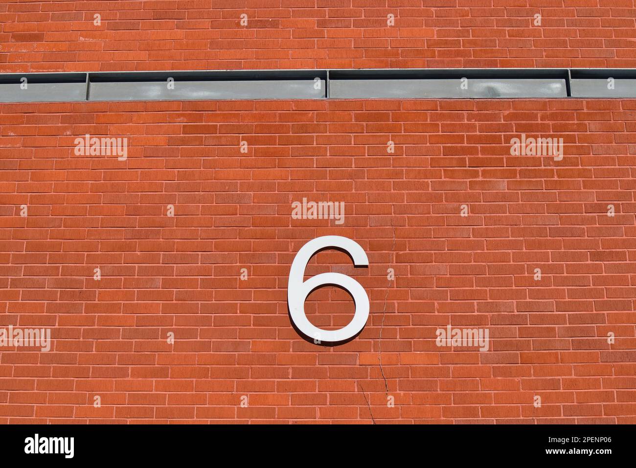 numero sei su un muro di mattoni all'aperto Foto Stock