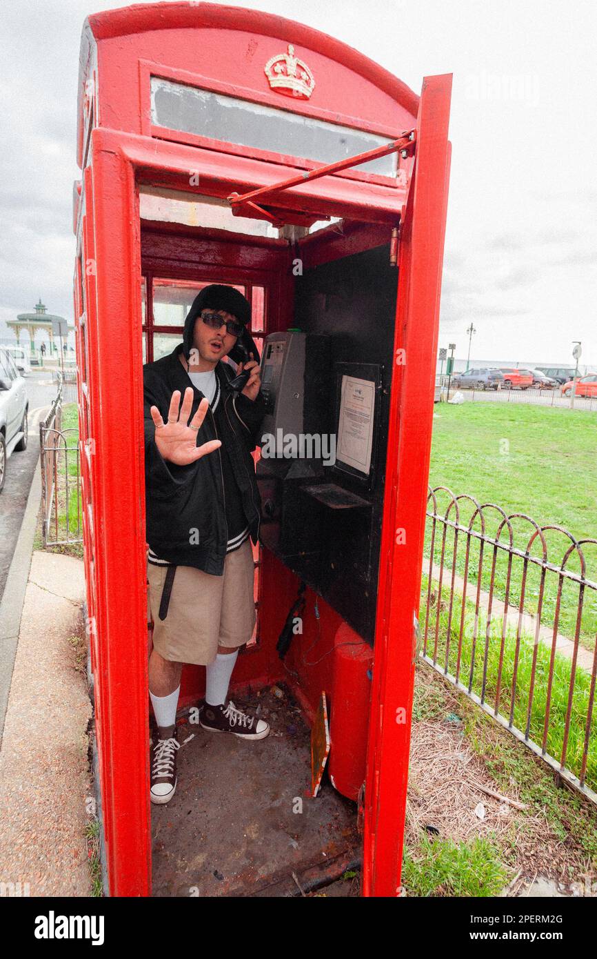 Giovane uomo in una scatola telefonica britannica - Brighton & Hove, East Sussex, UK Foto Stock