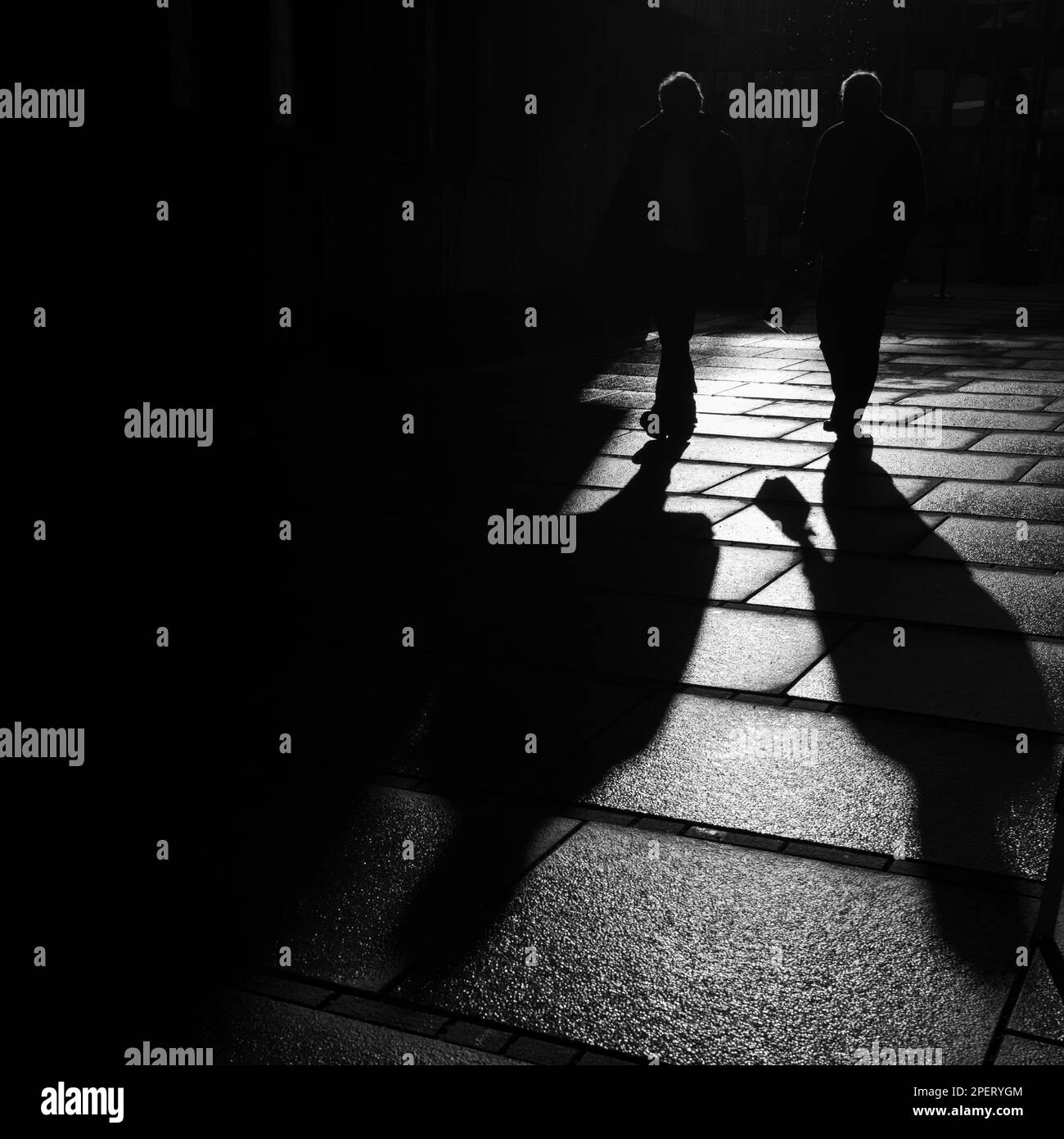 Un'immagine in scala di grigi di persone che camminano per strada al tramonto. Foto Stock