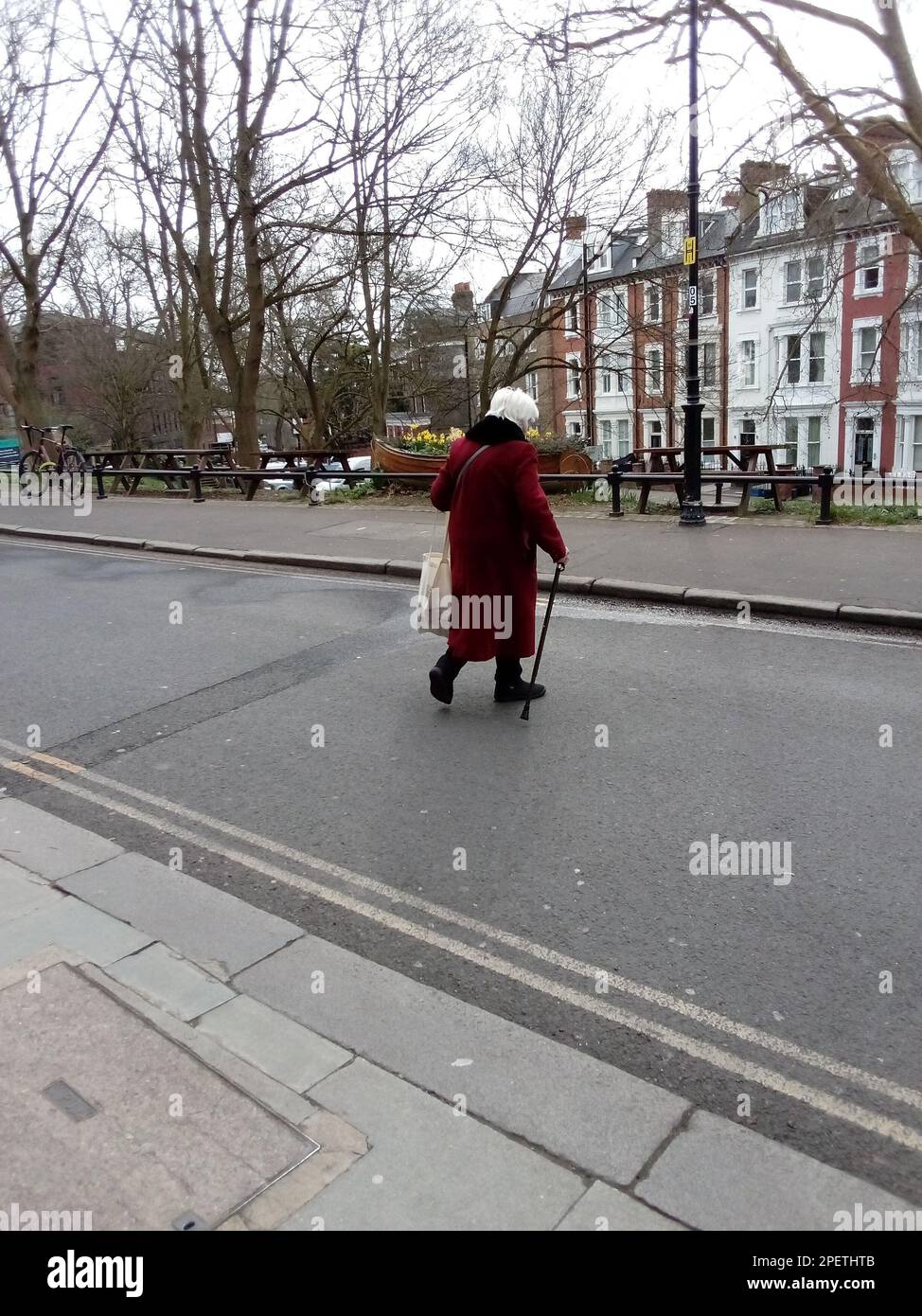 Anziana Signora che attraversa una strada a Londra UK Foto Stock