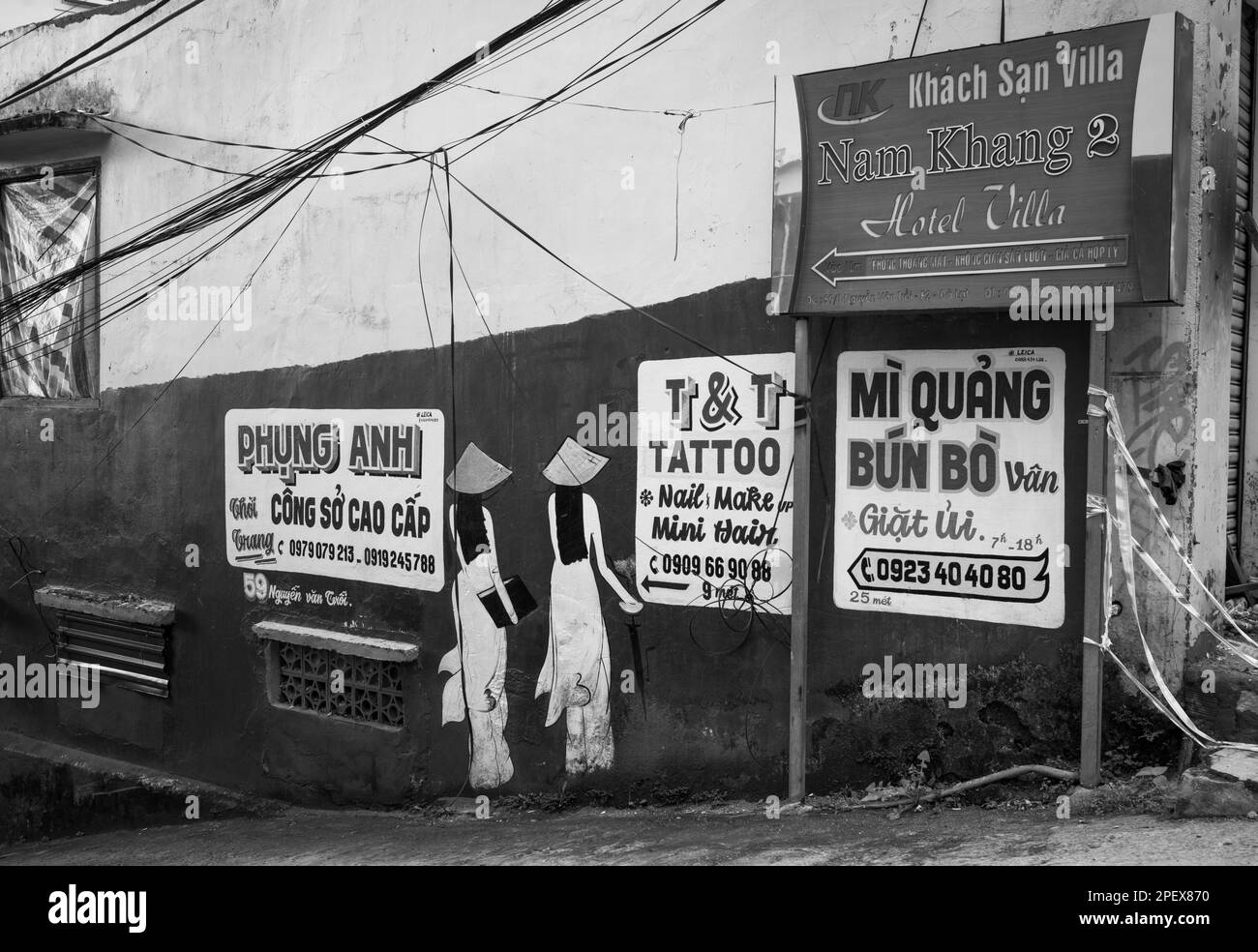 Annunci colorati dipinti per le aziende locali su un muro in una strada laterale a Dalat, Vietnam. Foto Stock