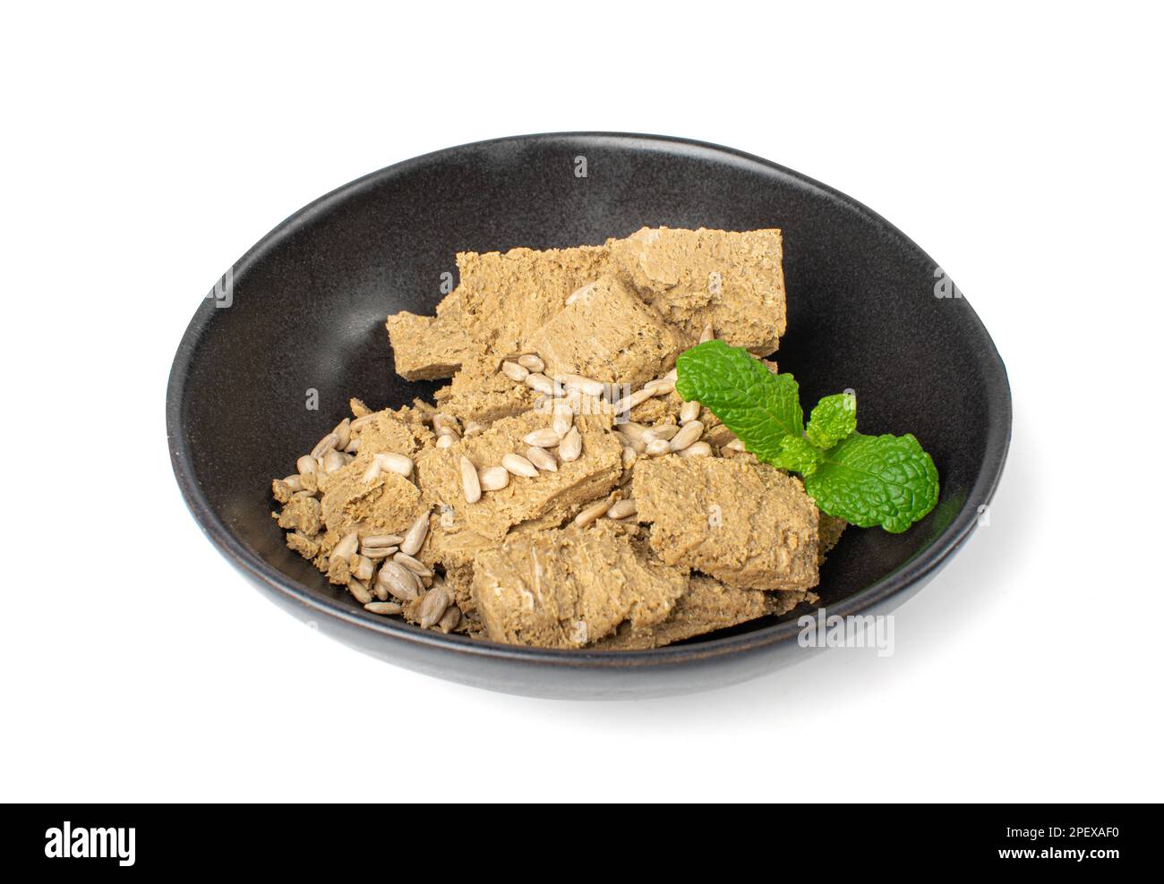 Pezzi di halva in ciotola nera isolata, girasole Halawa, Halvah o Halwa su sfondo bianco Foto Stock